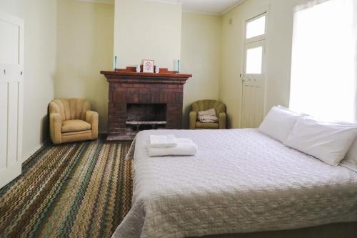 a bedroom with a bed and two chairs and a fireplace at Royal Hotel Capertee in Capertee
