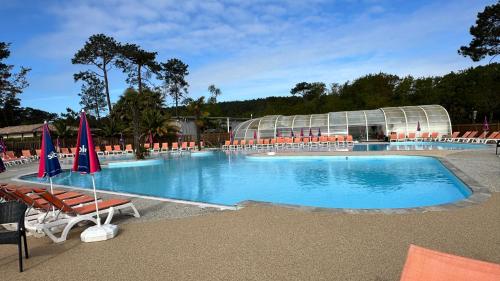 une grande piscine avec des chaises et un bâtiment dans l'établissement Entre Terre et Mer, à Lège-Cap-Ferret