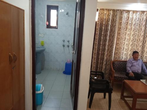 Un hombre sentado en una silla en un baño. en vella marina group of hotel Ravine, en Dharamshala