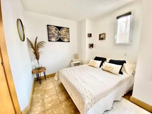 une chambre blanche avec un lit et une fenêtre dans l'établissement Le Bohème Charmant appartement meublé avec parking, à Amélie-les-Bains-Palalda