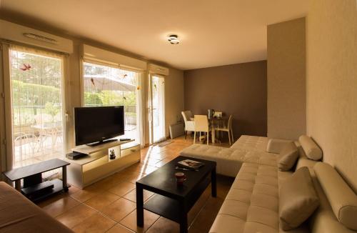 un salon avec un canapé et une télévision à écran plat dans l'établissement Logement avec grande terrasse., à Vétraz-Monthoux