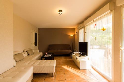 un salon avec un canapé et une télévision dans l'établissement Logement avec grande terrasse., à Vétraz-Monthoux