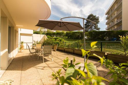 un patio avec un parasol, une table et des chaises dans l'établissement Logement avec grande terrasse., à Vétraz-Monthoux