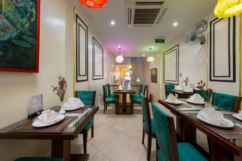 a dining room with wooden tables and green chairs at Bella Premier Hotel & Rooftop Skybar in Hanoi