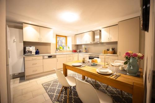 a kitchen with a wooden table and white cabinets at Villa Vanilla im Burgdorf 11 P. in Neidenstein