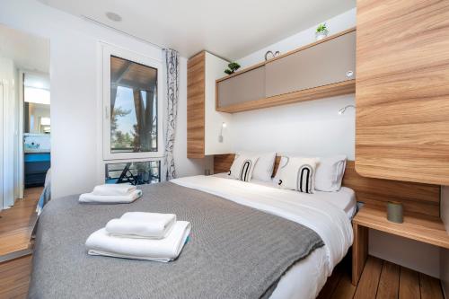 a bedroom with a large bed with two towels on it at Mobile home MAŠA 163, camp Porton Biondi in Rovinj