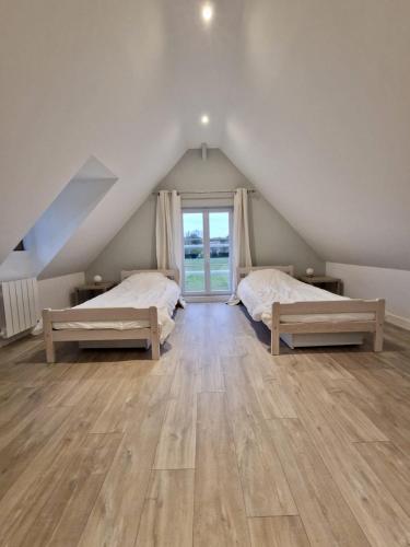- une chambre mansardée avec 2 lits et une fenêtre dans l'établissement Maison normande à la campagne, à Saint-Désir