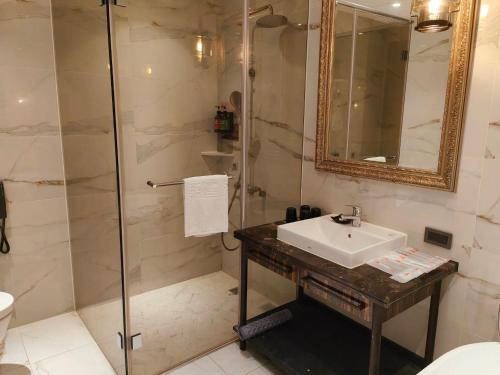 a bathroom with a sink and a glass shower at Saint Art Hotel in Beigang