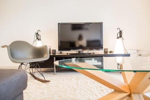 - un salon avec une télévision, une chaise et une table en verre dans l'établissement Belle villa-patio à 700m de l'océan, à Seignosse