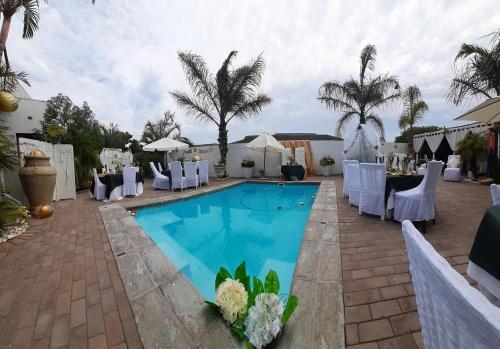 a swimming pool with white chairs and a table at Au Plais De Langebaan at Palm Tree Villa in Langebaan