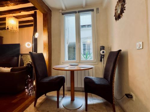 a small table and chairs in a room with a window at Luxury studio design by KENZO with Jacuzzi in Paris