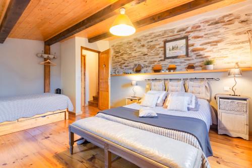 a bedroom with two beds and a stone wall at Le Gîte Dame Nature 