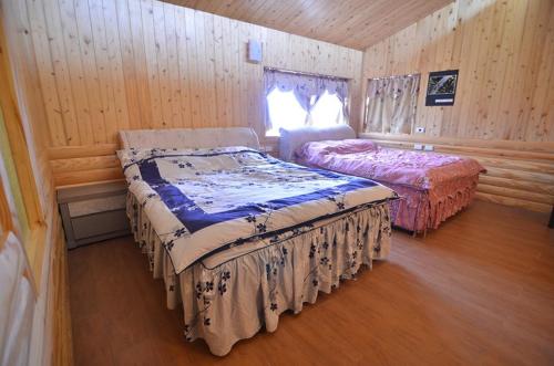 華陵里的住宿－拉拉山 桃花源農莊，木制客房内的一间卧室配有两张床