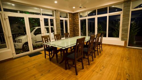 a dining room with a glass table and chairs at Carmel Top Munnar in Munnar