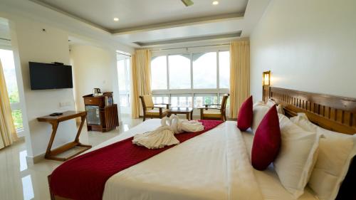Carmel Top Munnar في مونار: غرفة نوم مع سرير أبيض كبير مع وسائد حمراء
