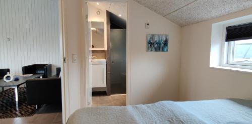 Schlafzimmer mit einem Bett, einem Schreibtisch und einem Fenster in der Unterkunft Ferie-Oasen i Øster Hurup in Øster Hurup