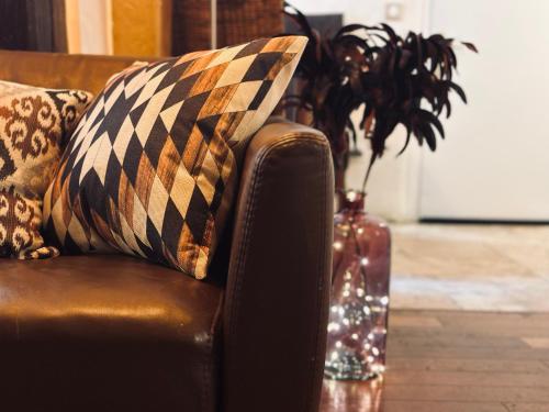 un canapé avec des oreillers et un vase avec une plante dans l'établissement Studio New design by KENZO experience, à Paris