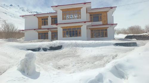 een huis bedekt met sneeuw voor de deur bij Moksha, Losar in Losar