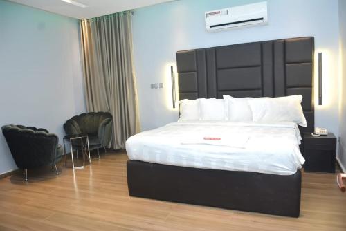 ラゴスにあるTripletee luxury hotelのベッドルーム1室(大型ベッド1台、黒いヘッドボード付)