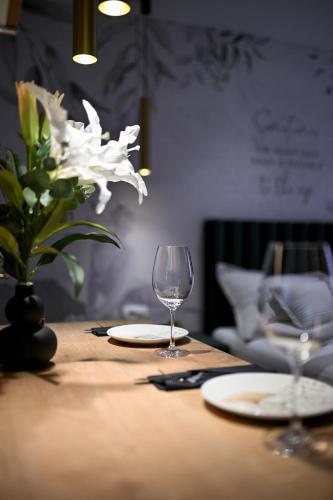 a wooden table with two glasses and a vase with white flowers at Apartments and Rooms Nekic in Zadar