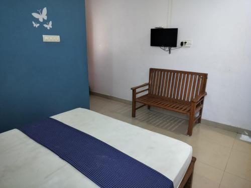 a bedroom with a bed and a chair and a television at Marudhan Grand in Kumbakonam