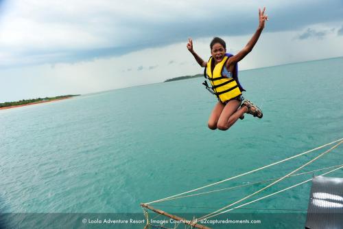a girl jumping off of a boat in the water at LooLa Adventure Resort in Telukbakau