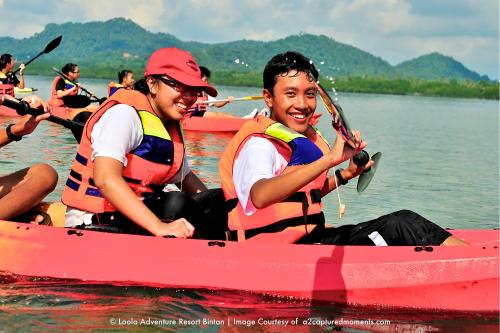 a group of people in a red boat on the water at LooLa Adventure Resort in Telukbakau