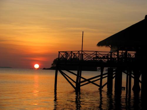 特魯克巴庫的住宿－盧拉冒險度假村，水面上的码头,背景是日落