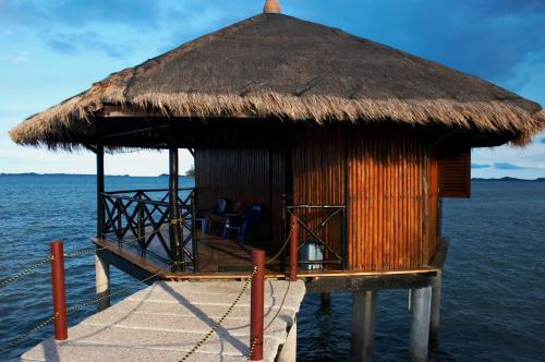 a shack on the water with a thatch roof at LooLa Adventure Resort in Telukbakau
