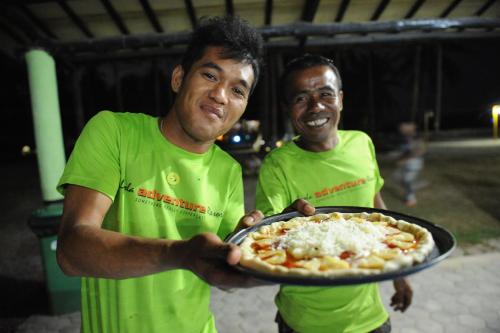two men are holding a pizza on a tray at LooLa Adventure Resort in Telukbakau