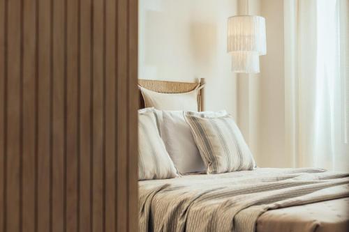 a bed with white sheets and pillows next to a window at Salty Angel Sea Front Villa in Laganas