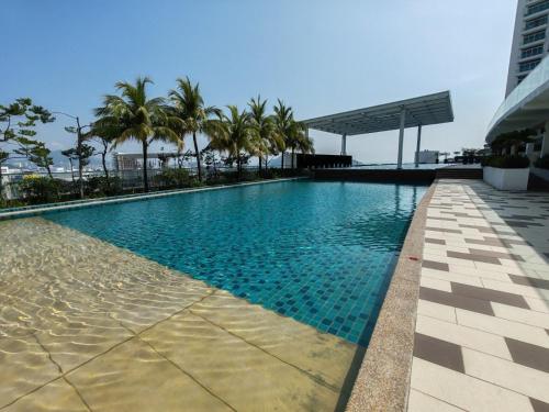 バヤンレパスにあるSeaview Condo 10pax #10minQueensbay #15minSpiceのヤシの木が茂る建物の屋上スイミングプール