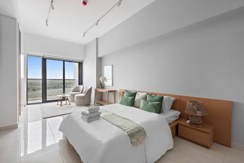 a white bedroom with a large bed and a desk at Charming and Spacious Studio in Dubai