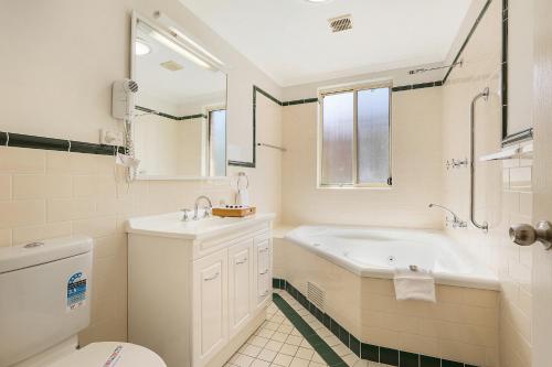 a bathroom with a tub and a sink and a toilet at Terralong Terrace Apartments in Kiama