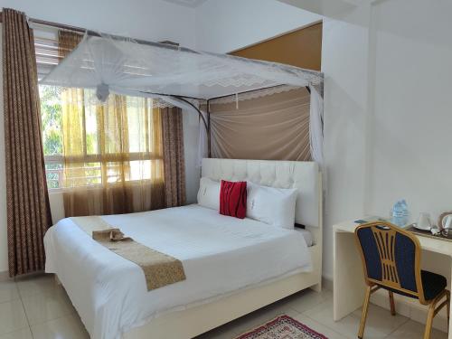 a bedroom with a white bed with a canopy at Garden Courts Hotel Masaka in Masaka