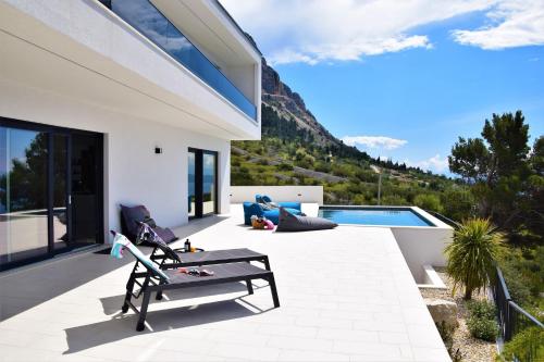 a patio with a bench and a swimming pool at Design Villa SkyBlue mit Pool und Panorama Meerblick in Podgora