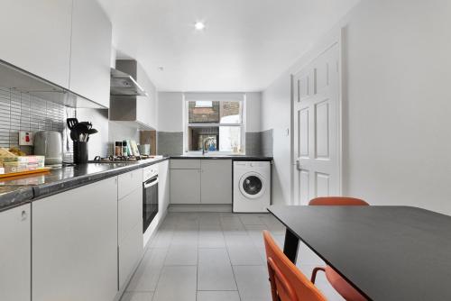 a kitchen with white cabinets and a black counter top at Former Victorian Bakery Conversion in the Heart of Highbury in London