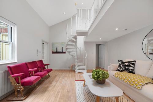 a living room with a couch and red chairs at Former Victorian Bakery Conversion in the Heart of Highbury in London