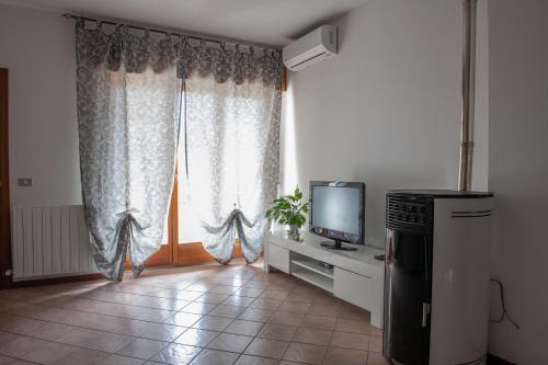 a living room with a television and a window at Casa Maya in Sarnano