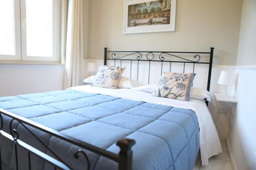 Una cama con sábanas azules y almohadas en un dormitorio en Cilento Suite - Louis XXII, en Agropoli