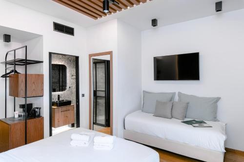 a white bedroom with two beds and a tv at Snob Athens in Athens