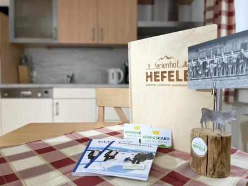 a table with a sign and a book on a table at Ferienhof Hefele Ferienwohnung Hopfensee mit KönigsCard in Hopferau
