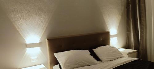 uma cama com duas almofadas num quarto com duas luzes em A casa di Rosy em Casalecchio di Reno