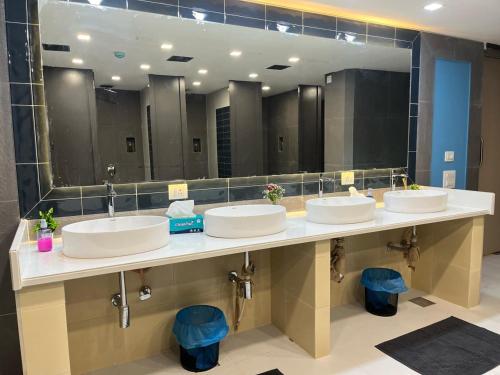 a bathroom with three sinks and a large mirror at OSTELO Mumbai Airport Hostel in Mumbai