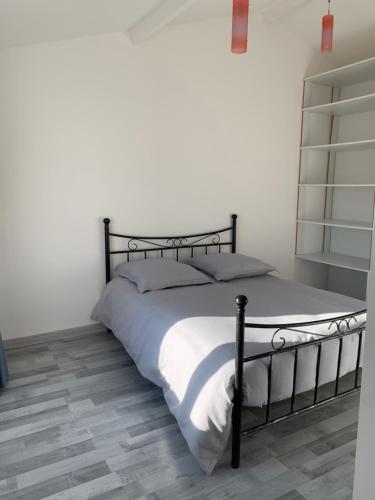 1 dormitorio con cama negra con sábanas blancas en Maison lumineuse aux portes de Montpellier, en Vailhauquès