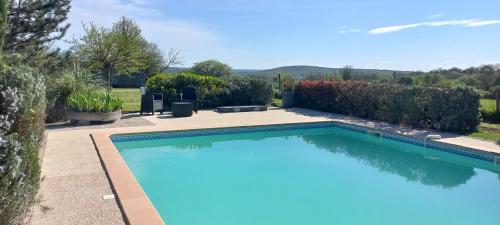 a large swimming pool in a yard with a garden at La Petite Grange in Saint-Martin-Labouval