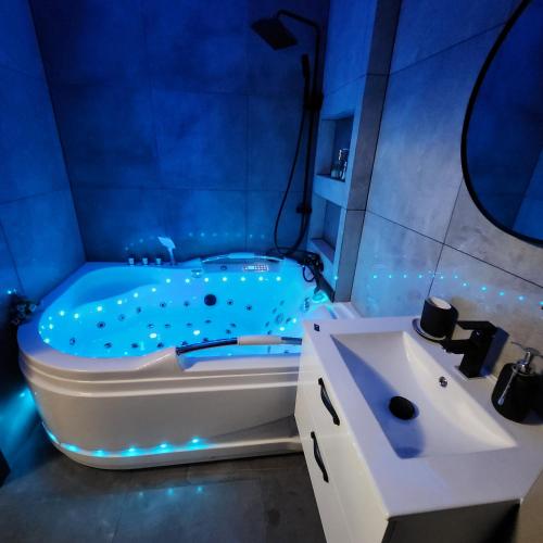 a blue bathroom with a tub and a sink at WARSZAWA CENTRAL HOUSE - Studios in Warsaw with Private Jacuzzi, full access to Sauna, Gym and Billards - Studia z prywatnym Jacuzzi oraz dostępem do sauny, siłowni i bilarda in Warsaw