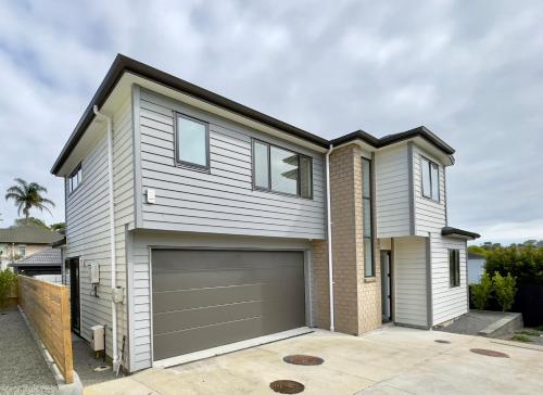 a house with a garage in front of it at Sky Stars Brand-new comfortable 3 & 4-bedroom Houses in Auckland