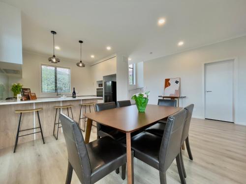 uma sala de jantar e cozinha com mesa e cadeiras de madeira em Glendowie Brand-new comfortable 3 & 4-bedroom Houses em Auckland