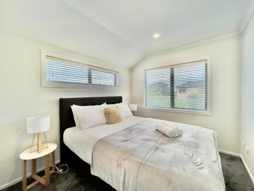 a bedroom with a large bed and two windows at Sky Stars Brand-new comfortable 3 & 4-bedroom Houses in Auckland